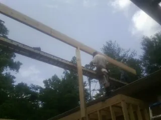 Carpenter setting a ridge beam over a new addition frame — Ice Dam Removal by Roofing Brothers in Wolf Creek