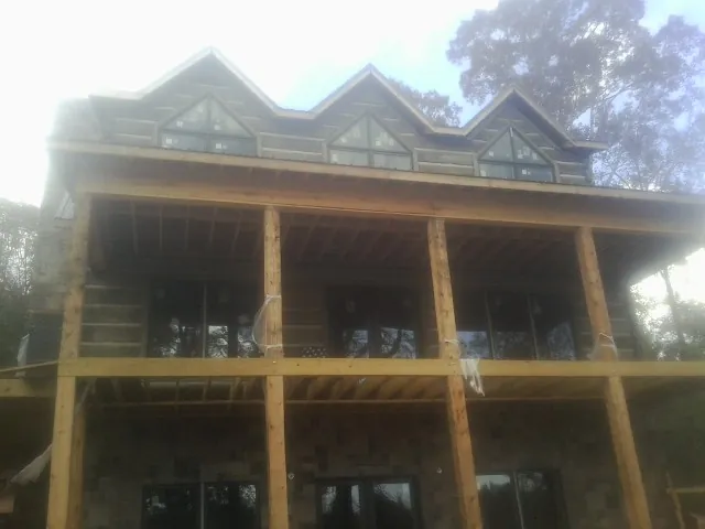 Dormers and porch framing on a large log home under construction — Roof Coating work by our crew in Wolf Creek