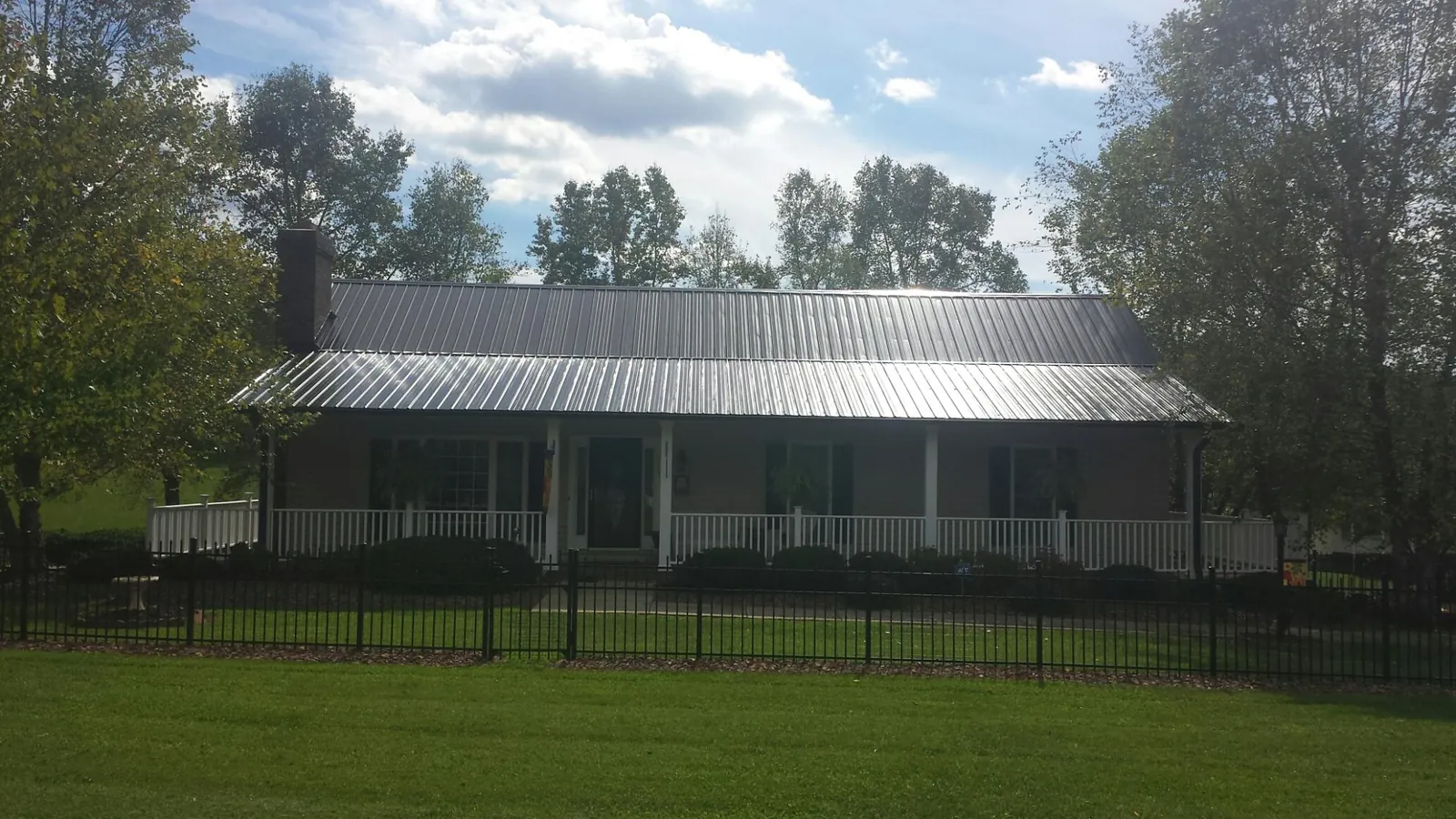 Gray metal roof on a brick ranch with a full width front porch — Gutter Guard Installation work by our crew in Wolf Creek