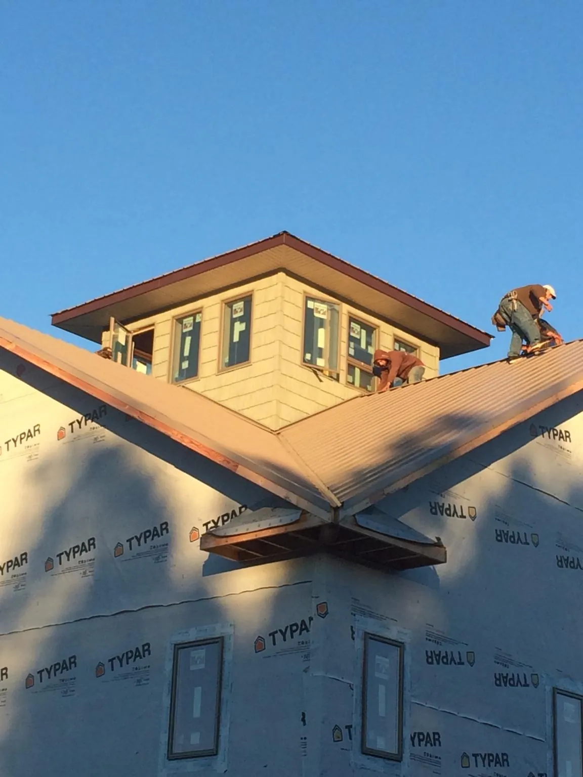 Roofers working around a rooftop cupola on a new metal roof at sunset — Roof Waterproofing in Wolf Creek by Roofing Brothers